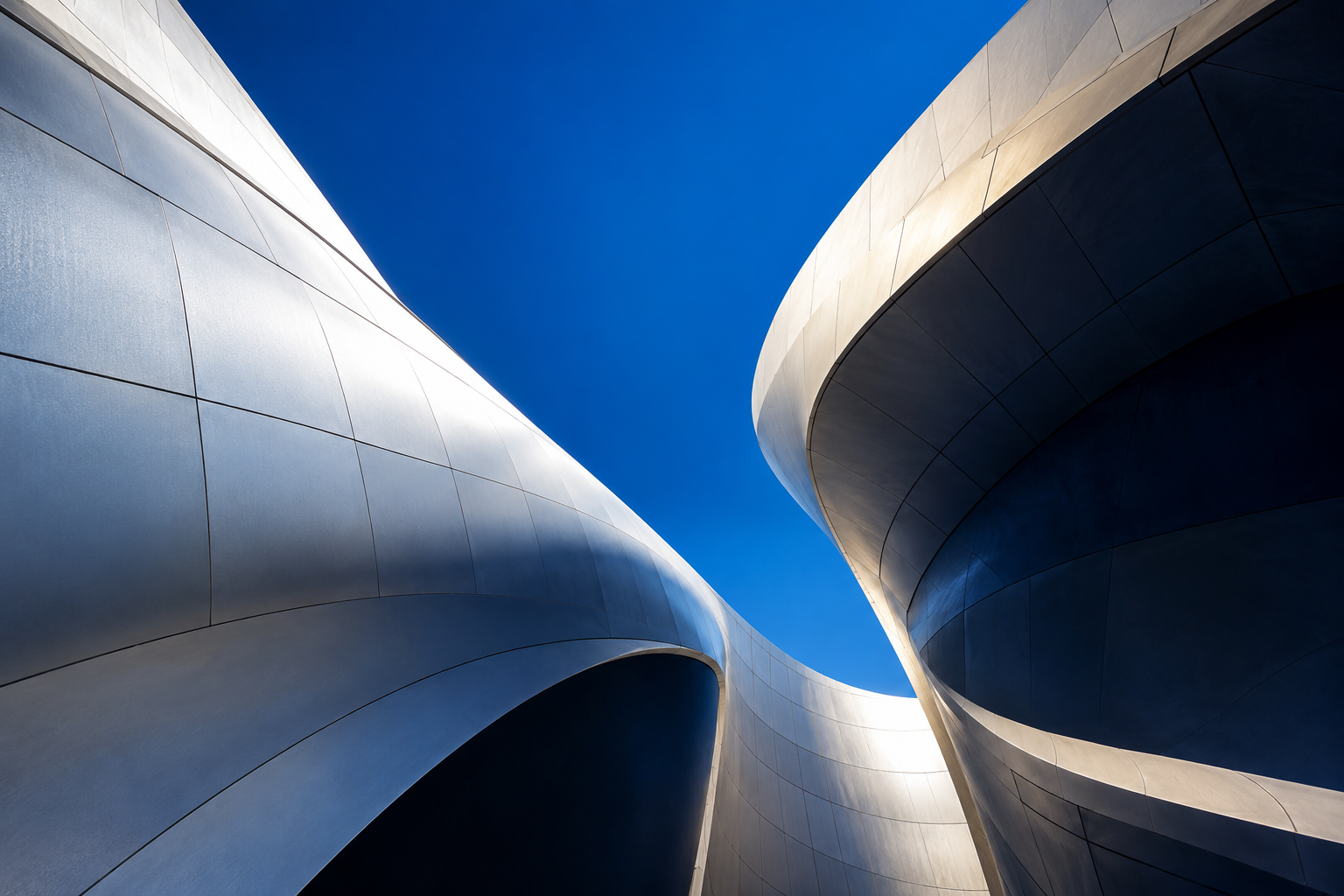 Illustrative architectural photograph of sweeping silver forms opening towards a blue sky